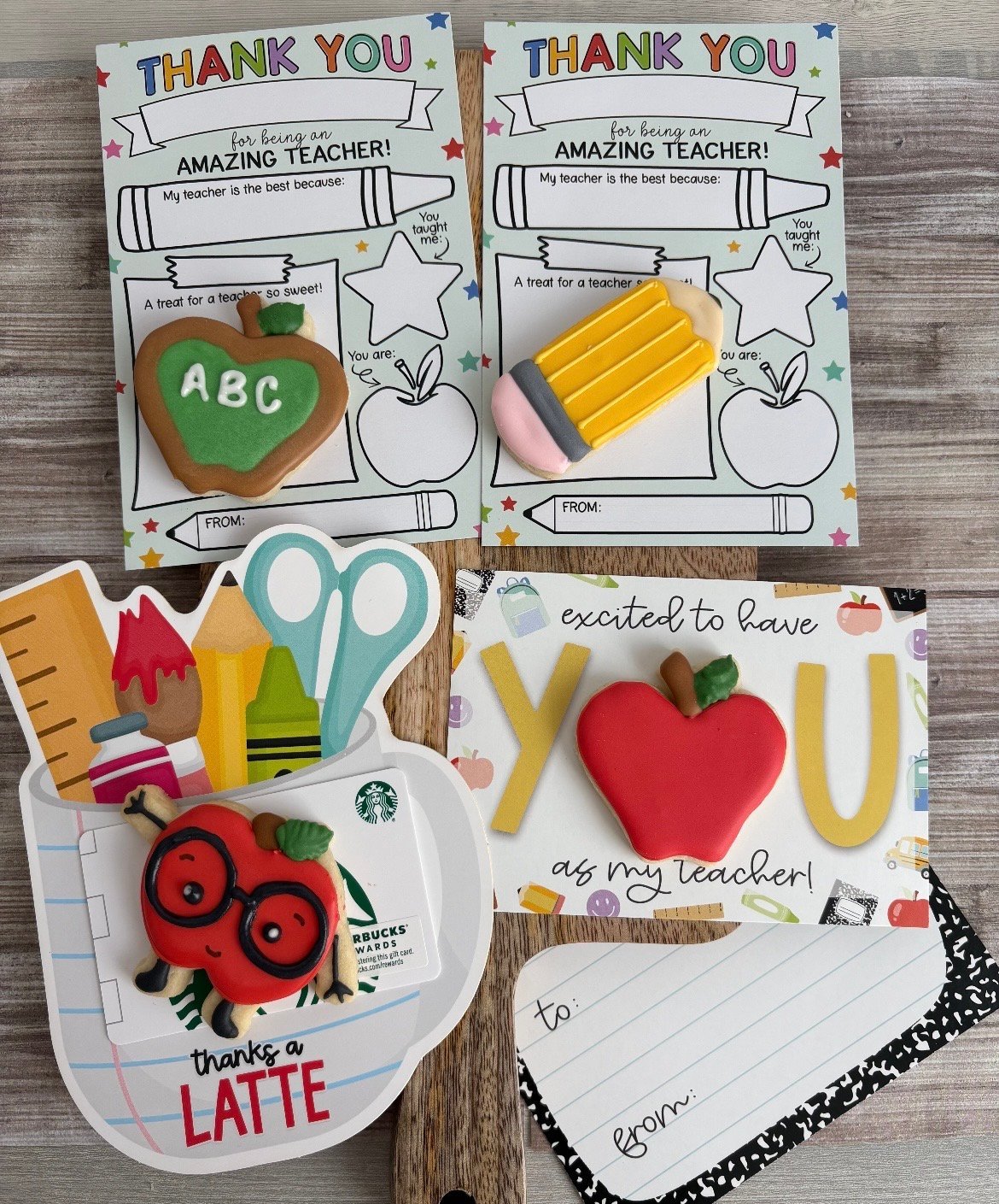 Collection of four handmade thank you cards for teachers, featuring colorful designs with apple, pencil, scissors, and coffee cup motifs on a wooden surface