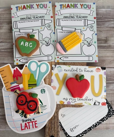 Collection of four handmade thank you cards for teachers, featuring colorful designs with apple, pencil, scissors, and coffee cup motifs on a wooden surface