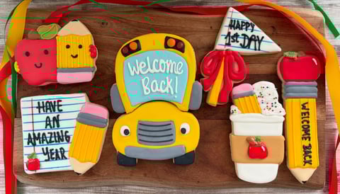 Colorful back-to-school decorations on wooden tray including yellow school bus, pencils, apple, coffee cup, and greeting signs